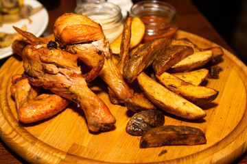 Fried chicken and french fries with sauce on a wooden plate.