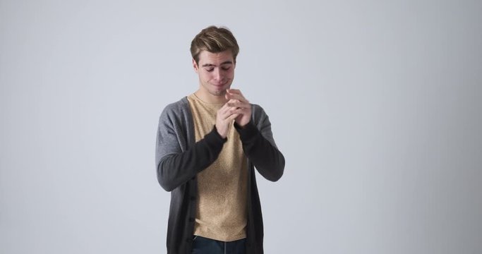 Bored young man clapping in sarcastic way over white background