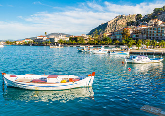 Fototapeta na wymiar Bright boats in the port of Nafplio city in Greece with sea promenade and fortress on the hill