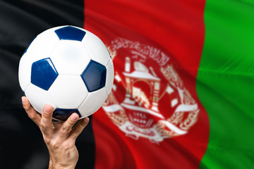 Naklejka premium Afghanistan soccer concept. National team player hand holding soccer ball with country flag background. Copy space for text.