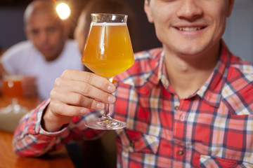 Cropped shot of a happy man toasting with his beer glass, copy space. Cheerful man having delicious beer at the bar