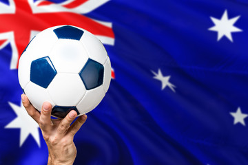 Australia soccer concept. National team player hand holding soccer ball with country flag background. Copy space for text.