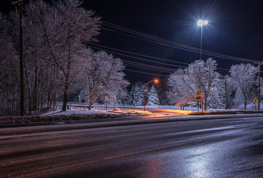 Night photo of the road and trees covered with white magical hoarfrost and sparkling sparkling ice, a winter night's tale. USA. Maine Portland Saco.