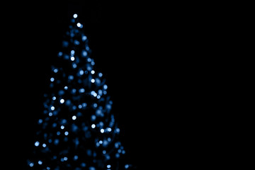 Blue lights of christmas tree blurred bokeh on dark background with copy space.