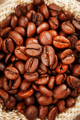 Freshly roasted aromatic coffee in a burlap bag on a wooden background.
