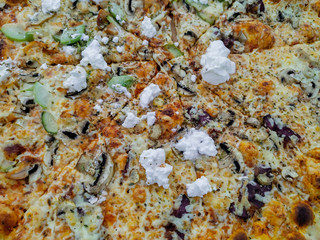 Delicious pizza closeup of a jumbo sized pizza served in a restaurant with different vegetables, cheese, cream and dough crust