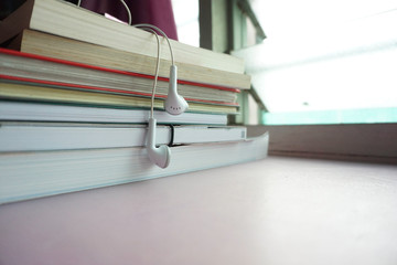 Stack of books on the table with earphone over the book.