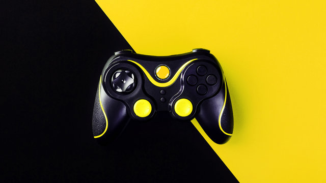 Black Gamepad On A Black-yellow Background, G. Game Concept. Device To Control And Control The Game.