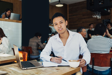 Asian man working on laptop in cafe