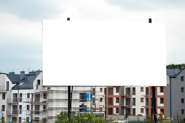 Obraz premium Blank white advertising billboard in the front of construction site on residential area