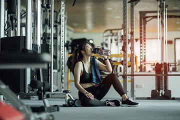 Girl drinking water in gym after workout. Lens flare,fitness concept.