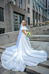 Obraz premium portrait of a beautiful bride in long dress and viel on the background of a business center