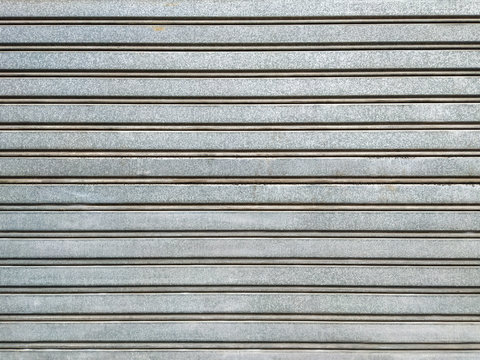 Grey metallic garage door for parking car and for safety, made of stainless steel but with signs of age and dirt