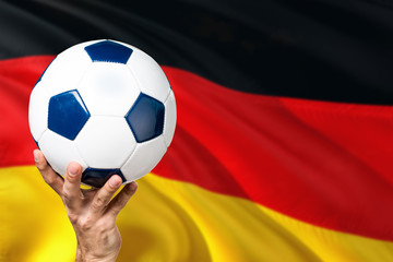 Naklejka premium Germany soccer concept. National team player hand holding soccer ball with country flag background. Copy space for text.