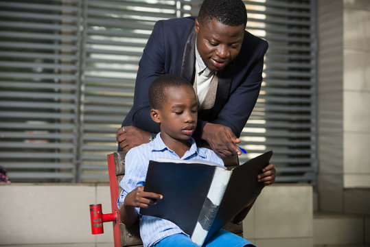 Businessman reading a book to his child outdoors