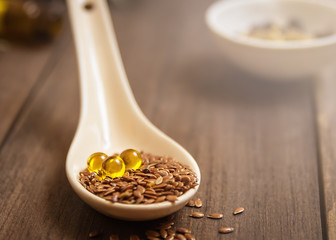 Flaxseed oil in pills on a wooden background. Phytotherapy. Linum usitatissimum oil. Homeopathy. Line seed oil. Alternative medicine.