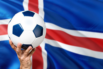 Fototapeta premium Iceland soccer concept. National team player hand holding soccer ball with country flag background. Copy space for text.