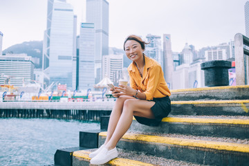 Fototapeta na wymiar Cheerful Asian woman sitting on steps at pier