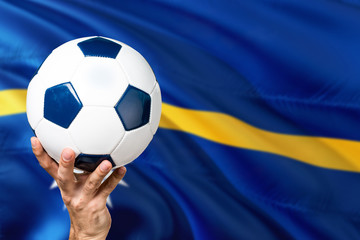 Naklejka premium Nauru soccer concept. National team player hand holding soccer ball with country flag background. Copy space for text.