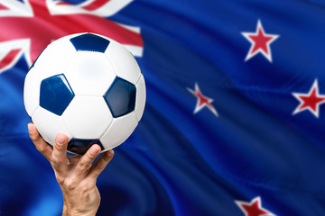 Naklejka premium New Zealand soccer concept. National team player hand holding soccer ball with country flag background. Copy space for text.