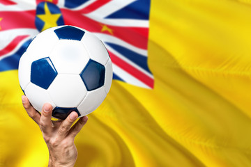 Niue soccer concept. National team player hand holding soccer ball with country flag background....