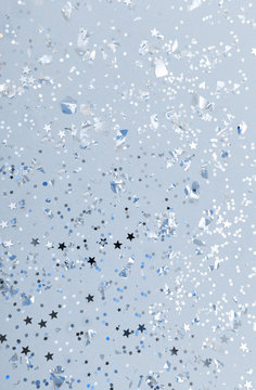 Christmas festive banner background: confetti with sparkling glitter and stars on blue background. Festive and bright. Top view, flat lay.