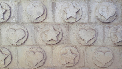 repeating hearts and stars on a gray concrete wall, a wall of love.