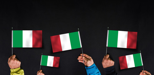 Hands holds flags of Italy on dark background