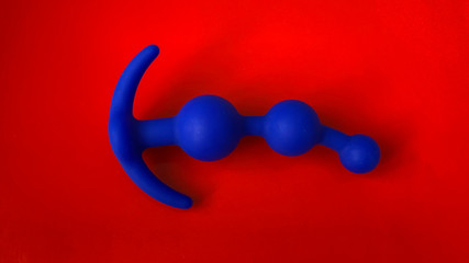 Blue anal plug for sex. On red background. Useful for sex shop or adults