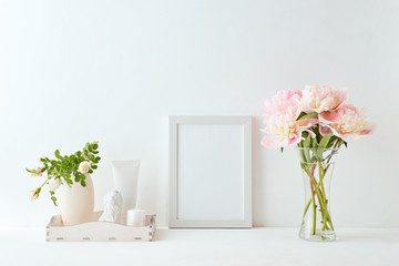 Home interior with decor elements. White frame, pink peonies in a vase, interior decoration