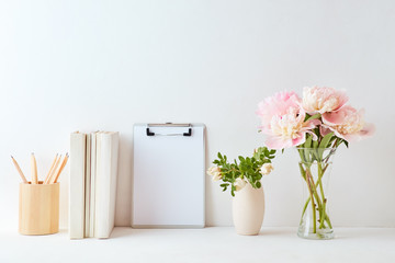 Home interior with decor elements. Mockup clipboard, pink peonies in a vase, interior decoration