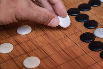 Plakat Go board game playing. A competitor is placing a marble piece on a Go board game
