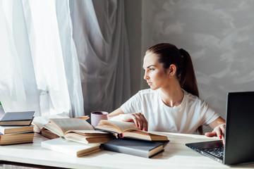 girl works at the computer reads books