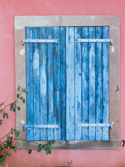 vieux volets bleus fermés sur maison rose