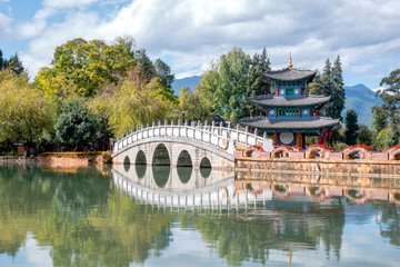 Fototapeta premium Beautiful view of the Jade Dragon Snow Mountain and the Suocui Bridge over the Black Dragon Pool in the Jade Spring Park, Lijiang,