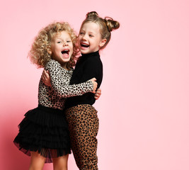 Nice and pretty kid girls friends sisters in leopard print clothes pants and sweater are hugging happy screaming