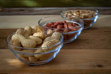 arachidi in 3 ciotole di vetro su tavolo di legno