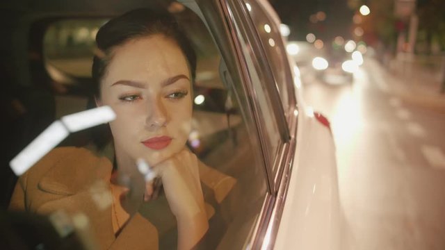Young smiling woman in the backseat of the car is looking through the window