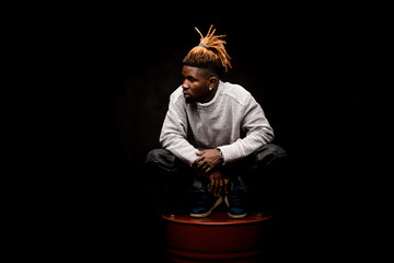 Afro american guy squatting on a barrel