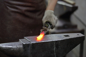Forging an iron handmade product in a craft forge workshop