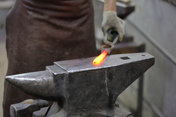 Forging an iron handmade product in a craft forge workshop