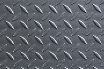 Industrial wallpaper of functional anti-slip metal tread plate in grey silver color and rough raised surface pattern. Creative lighting macro photography of construction for catwalks, stairs, walkway.