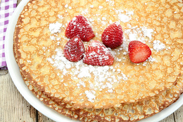 Breton crêpes and strawberries on a wooden table