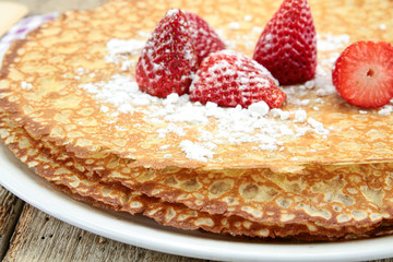 Breton crêpes and strawberries on a wooden table
