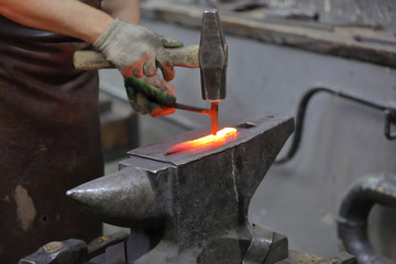 Forging an iron handmade product in a craft forge workshop