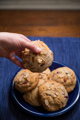 Platter of fresh scones with wooden, blue background and hand picking up scone