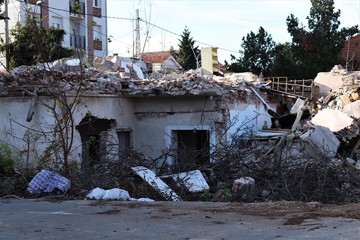 Old ruined house with broken glass, with a pile of construction debris and branches.