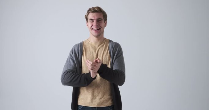 Excited young man clapping hands and cheering over white background