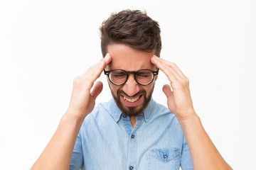 Frustrated unhappy guy touching head with pain grimace. Handsome young man in casual shirt and...