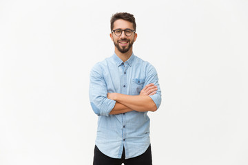 Happy laughing guy posing with arms folded. Handsome young man in casual shirt and glasses standing isolated over white background. Male portrait concept - obrazy, fototapety, plakaty
